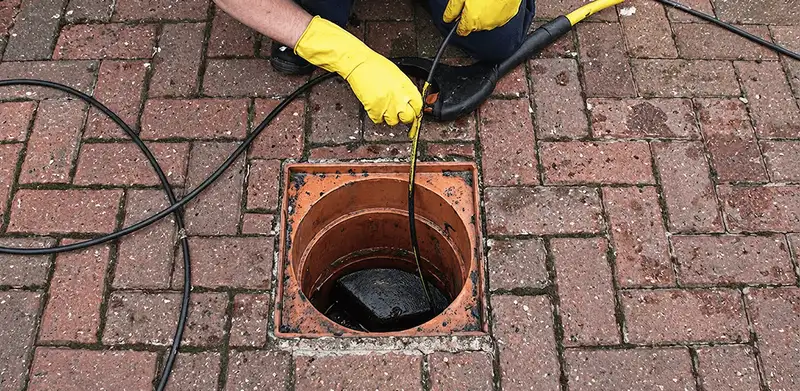Drain cleaning technician using a drain snake to clear a clogged drain in Sterling Heights, MI