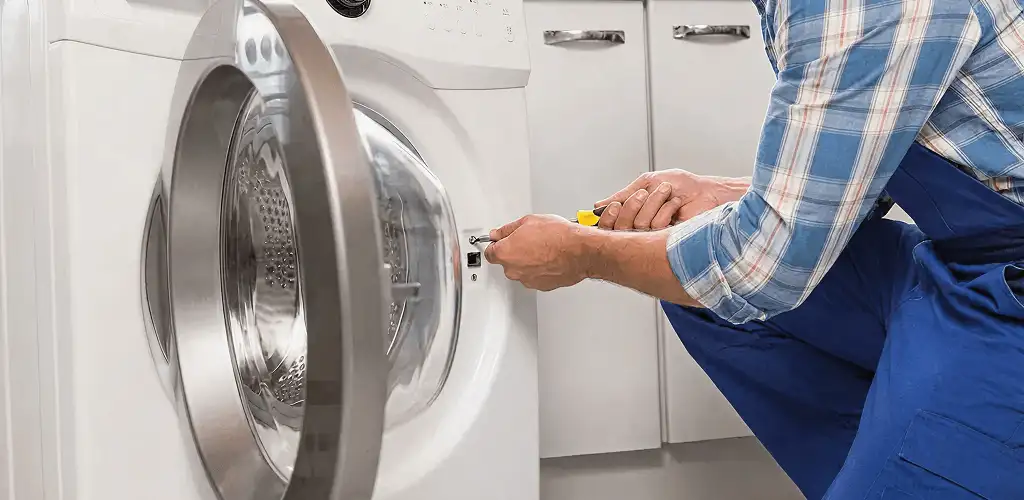Handyman repairing a clothes dryer and checking electrical connections in Sterling Heights, MI