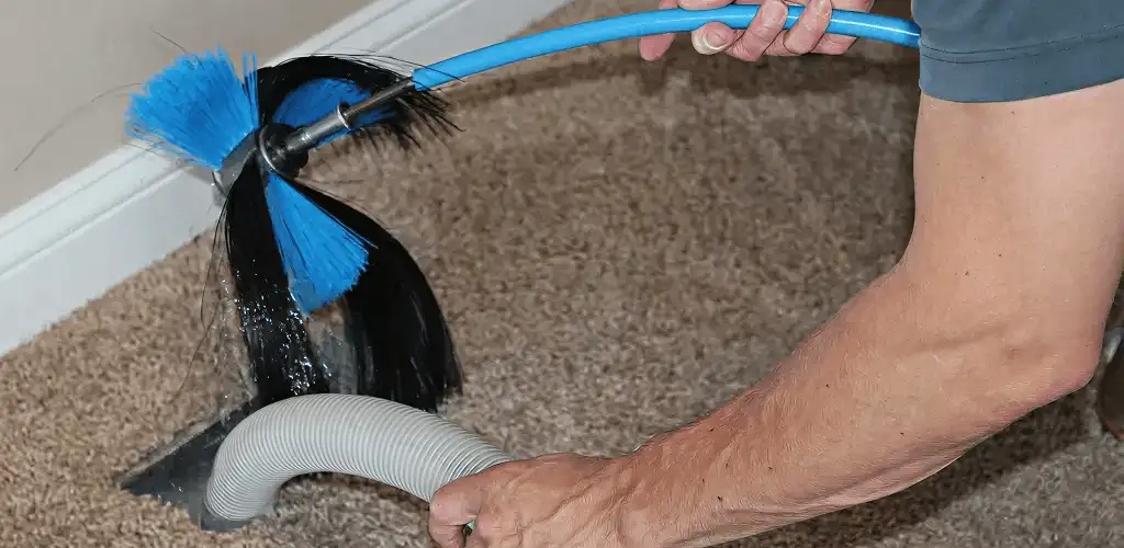 Dryer vent cleaning technician brushing lint from a vent line in Sterling Heights, MI