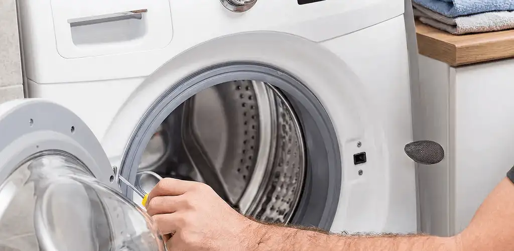 Handyman repairing a front-load washing machine and inspecting the drum in Sterling Heights, MI